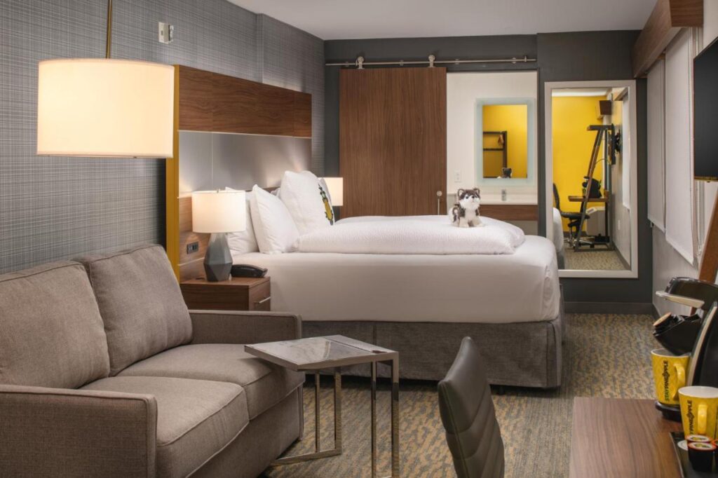 Quarto do Staypineapple, Hotel Z com uma cama de casal e um sofá lado a lado. Ao fundo estão um armário e um espelho. A foto está no post de onde ficar em San Diego.