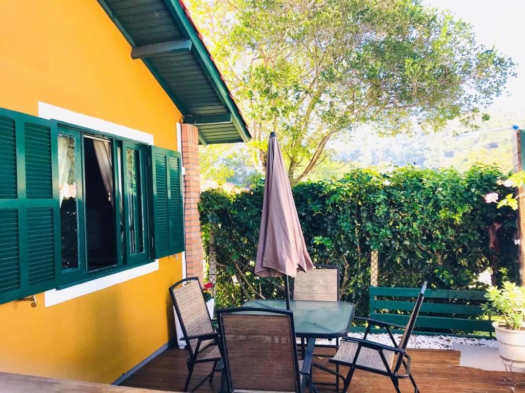 Frente da Casa Chale 10 Florianópolis quadrada com quatro cadeiras e mesa quadrada do lado direito e do lado esquerdo a estadia.