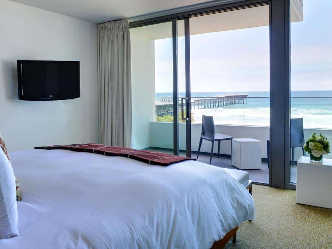 Quarto do Tower 23 Hotel . Uma cama de casal está virada para uma grande varanda com vista direta da praia. Uma tv está na parede do lado esquerdo. A imagem ilustra o post de onde ficar em San Diego.