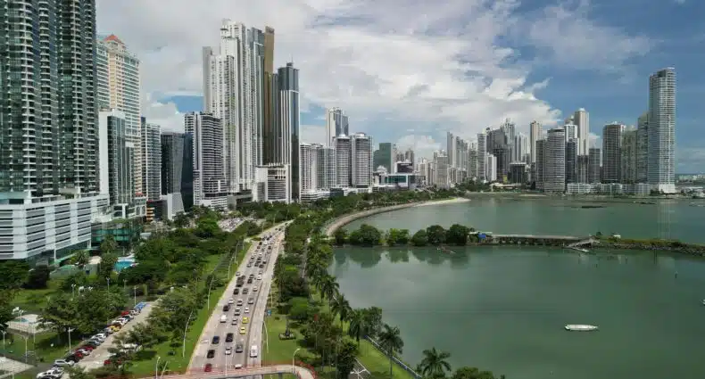 Vista aérea de um amplo horizonte urbano da Cidade do Panamá. Existem prédios altos, uma estrada movimentada, espaços verdes e um corpo d'água em primeiro plano. A foto é capa do post de o que fazer na Cidade do Panamá.