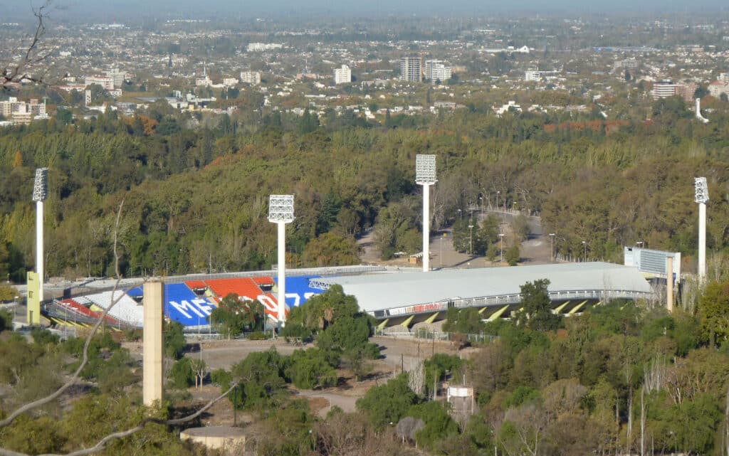 Vista aérea do Estádio Malvinas Argentinas cercado por árvores e uma paisagem urbana ao fundo. Foto para ilustrar post sobre o que fazer em Mendoza.