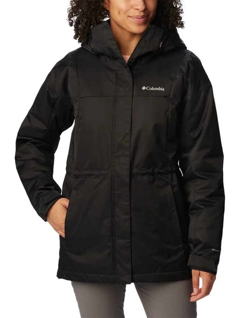 Pessoa vestindo uma jaqueta preta da Columbia com as mãos nos bolsos, capuz e logotipo visível no peito. Essa é a Jaqueta Columbia Feminina Hikebound Longa Insulated.