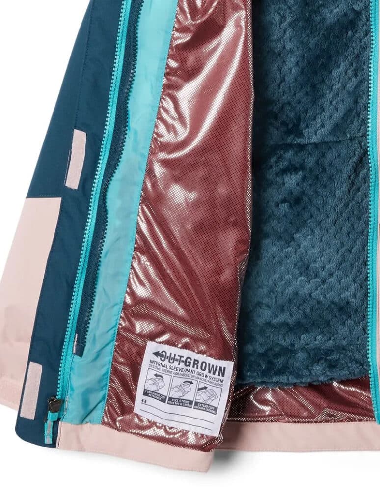 Close do interior de uma jaqueta mostrando um zíper azul-petróleo, forro de cetim rosa, etiqueta de tamanho e seção de lã texturizada preta.