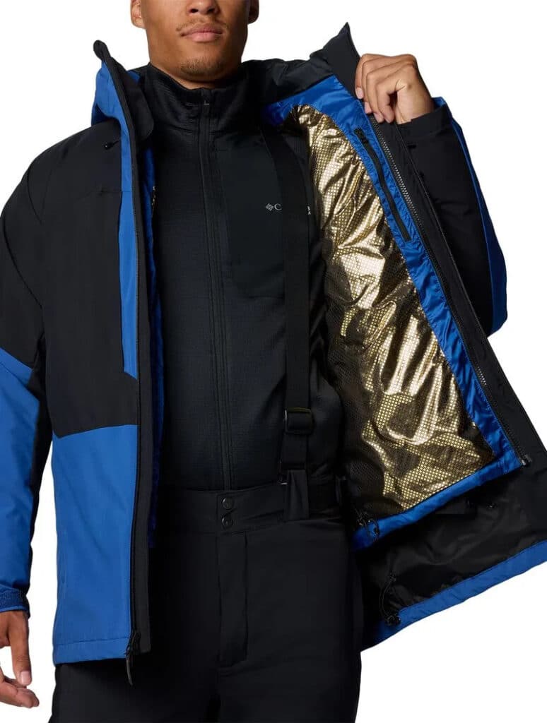 Pessoa vestindo uma jaqueta de inverno preta e azul, abrindo-a para mostrar o forro interno dourado.