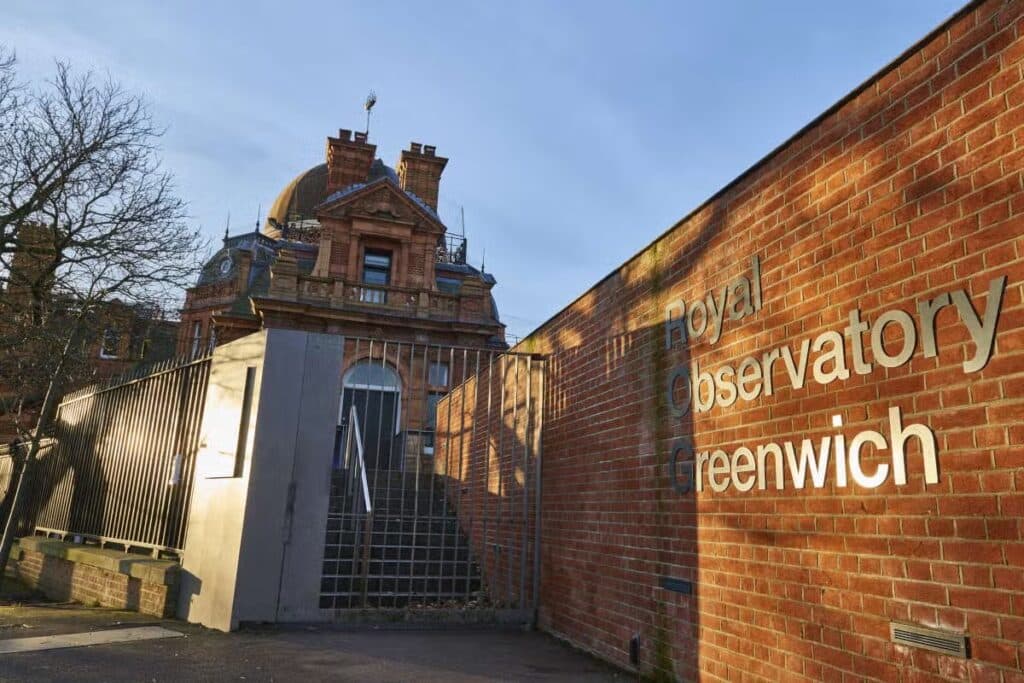 Entrada para o Observatório Real de Greenwich, com um edifício de tijolos com uma cúpula e uma placa em uma parede de tijolos. A imagem ilustra o post sobre roteiro para Londres.