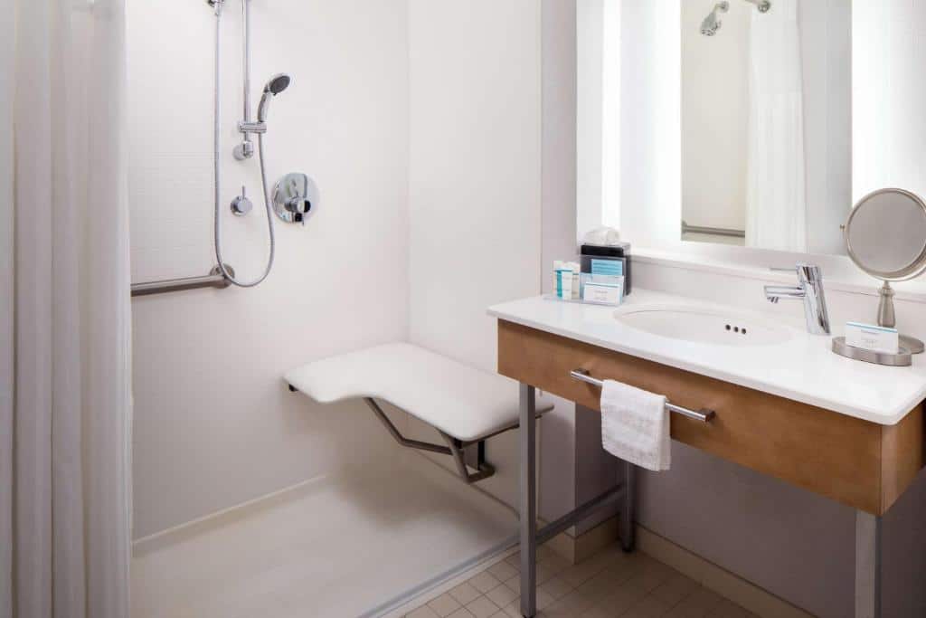 Banheiro acessível do Hampton Inn & Suites by Hilton Miami Downtown/Brickell com chuveiro, bancada, pia, espelho e toalha.