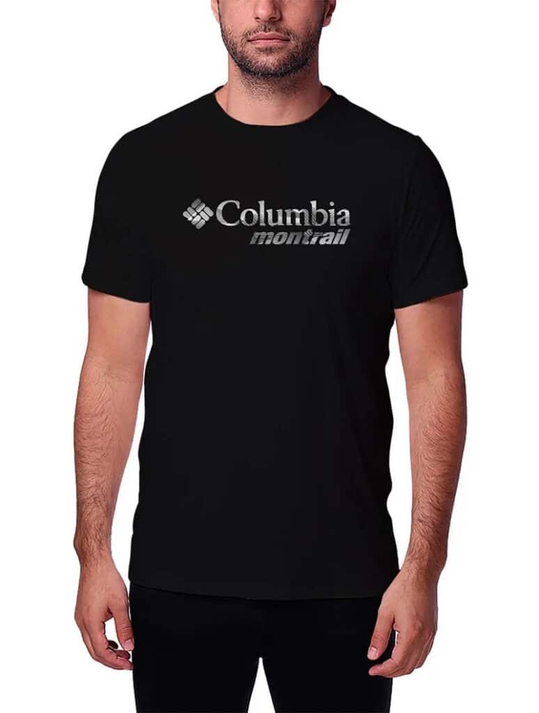 Homem vestindo uma camiseta preta com o logotipo "Columbia Montrail" na frente, em pé sobre um fundo branco liso.