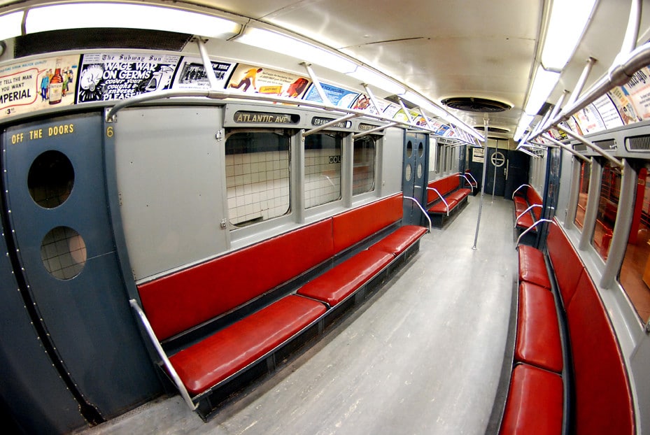 Interior de um vagão do Museu do Trânsito de Nova York - MTA Museum com assentos vermelhos e anúncios retrô, com placas para a estação Atlantic Ave. Imagem para ilustrar post sobre museus em Nova York.