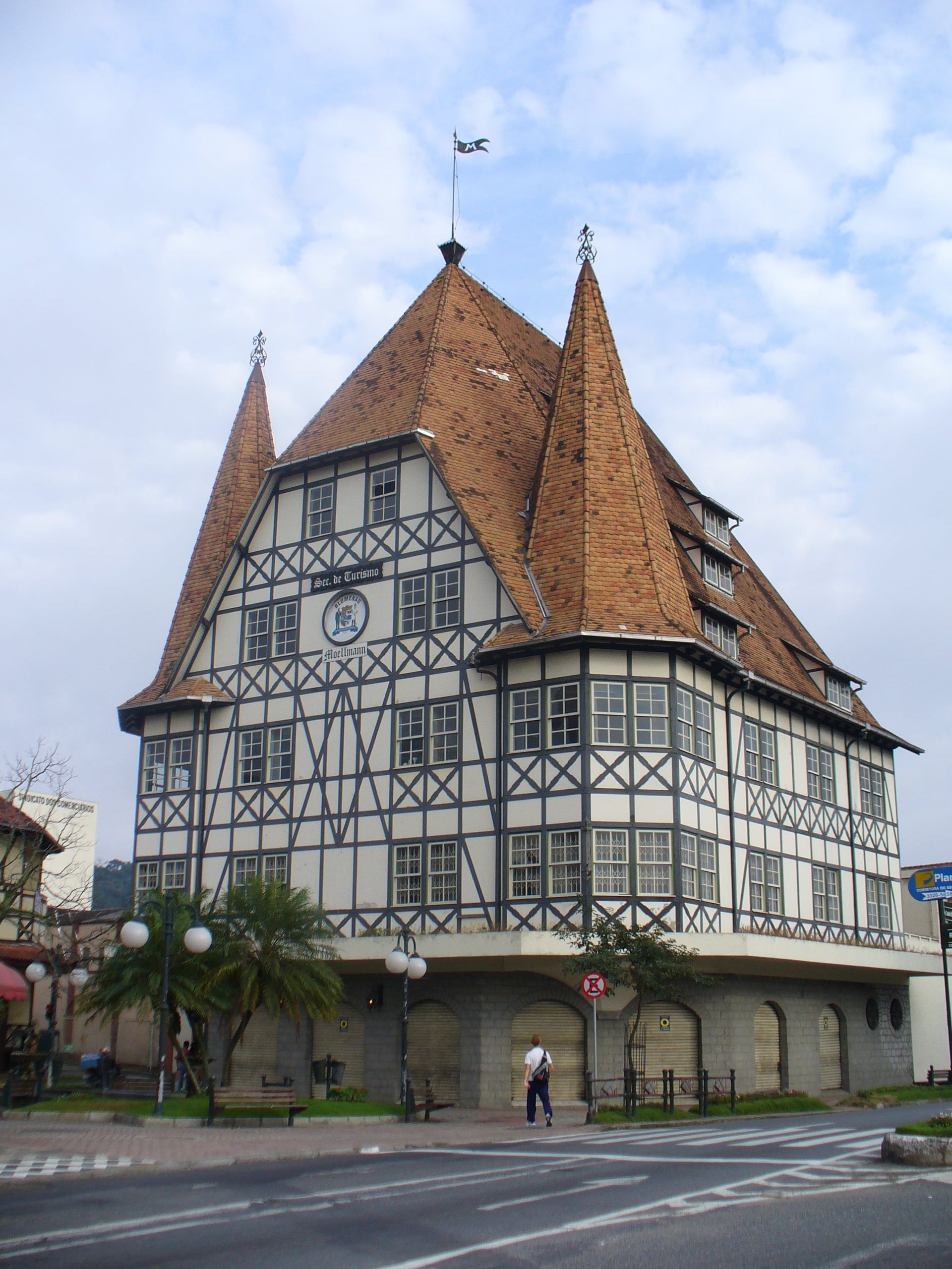Castelinho da Havan em enxaimel com telhados íngremes e pontiagudos e um cata-vento no topo, localizado em uma rua com faixa de pedestres. Imagem para ilustrar post sobre o que fazer em Blumenau.