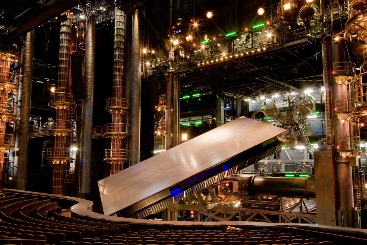 Configuração de palco do espetáculo KÁ", do Cirque du Soleil em Las Vegas. Há uma grande plataforma retangular inclinada em um ângulo. Várias luzes e estruturas mecânicas são visíveis.