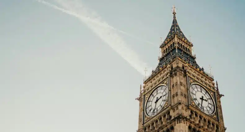 A icônica torre do relógio de Londres, frequentemente associada ao Big Ben, contra um céu azul com uma tênue esteira de condensação acima dela. Esse é um dos pontos turísticos da Inglaterra.