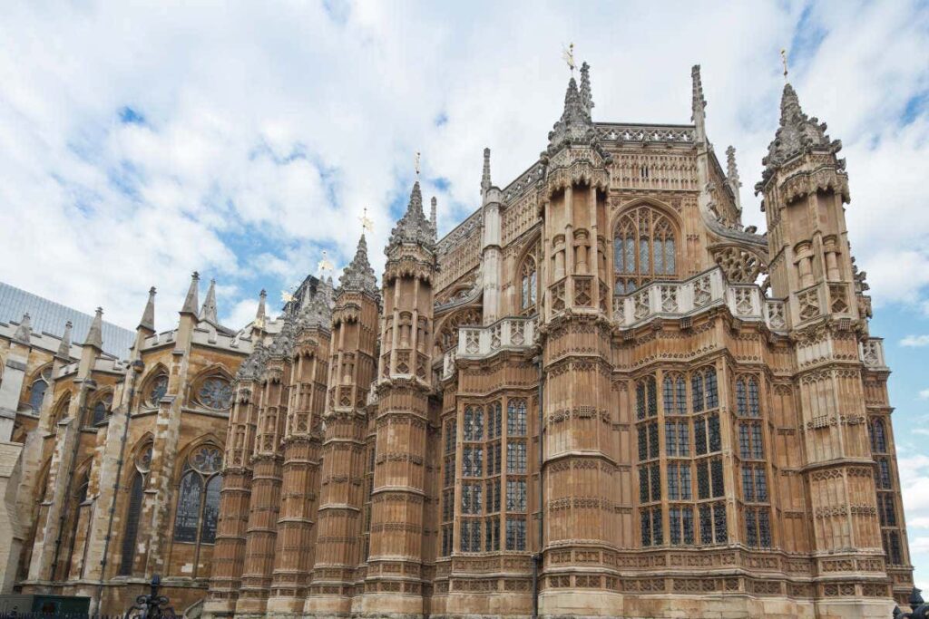 Exterior da catedral em estilo gótico, com torres ornamentadas e arquitetura detalhada, vista em um dia parcialmente nublado.