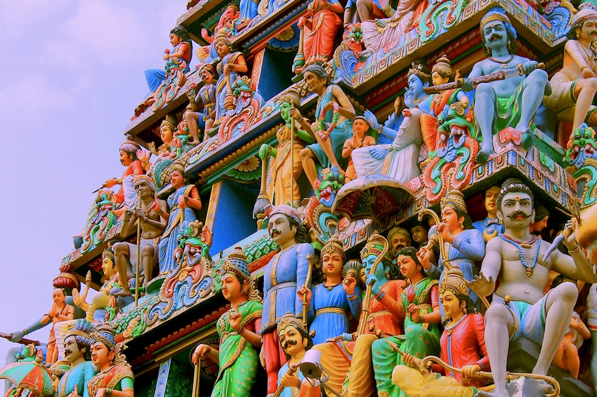 Uma vista detalhada da fachada colorida do Templo Sri Mariamman adornado com inúmeras divindades e figuras vibrantes e intrincadamente esculpidas.