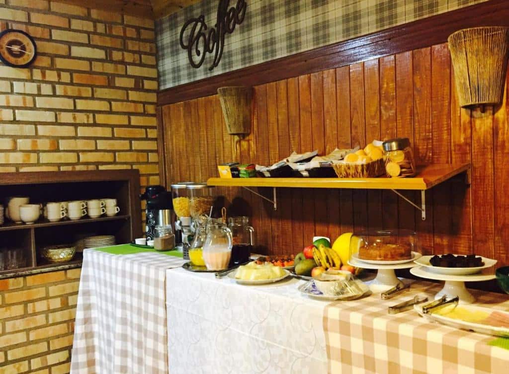 Um buffet de café da manhã com frutas, doces, bebidas e cereais em mesas cobertas com tecido xadrez em uma sala aconchegante, no Villa Apart Hotel.