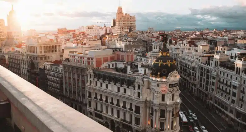 Uma vista da cidade de Madri ao pôr do sol, com o edifício Metropolis e a arquitetura histórica ao redor. Ilustra o eSIM Madri.