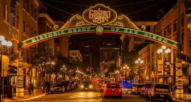 Vista noturna da placa do Gaslamp Quarter sobre uma rua movimentada no centro de San Diego, com carros e prédios iluminados. Imagem para ilustrar post sobre eSIM San Diego.