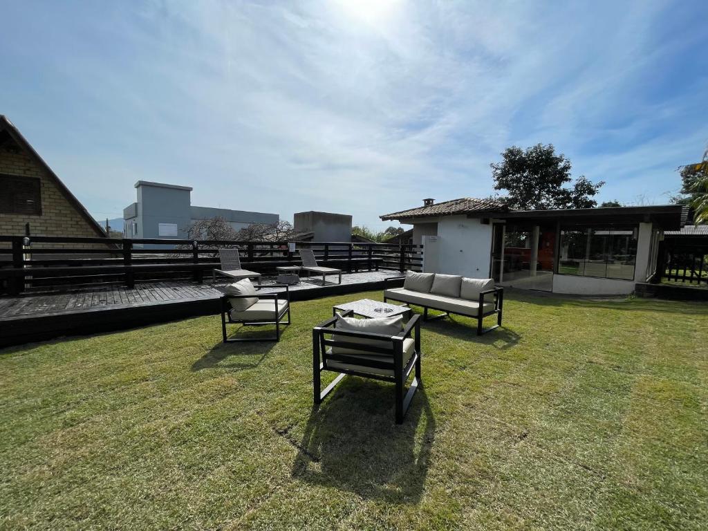 Pátio com mobília externa em um gramado, deck de madeira e uma casa ao fundo sob um céu azul, na propriedade no Rosamar Suites.