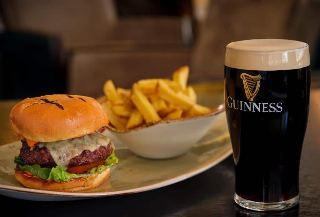 Um cheeseburger com alface e tomate, uma tigela de batatas fritas e uma caneca de Guinness em uma mesa, servido no The Westin Dublin.