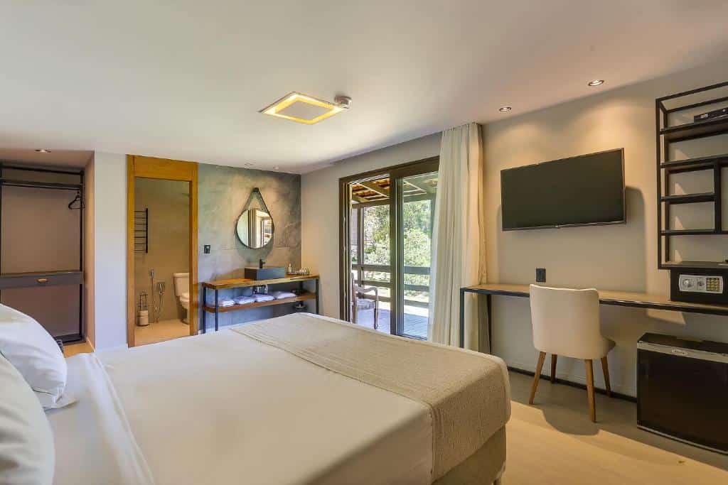 Quarto no Boqueirão Hotel Fazenda com cama de casal, escrivaninha, TV, armário aberto e banheiro com chuveiro de vidro e penteadeira, para representar pousadas em Lages