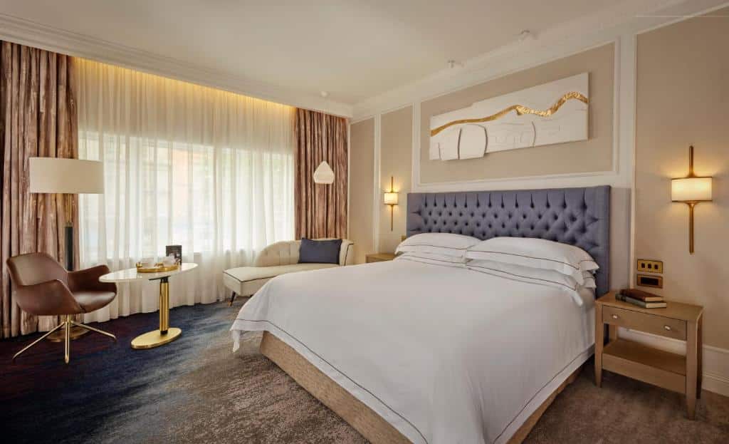 Quarto no The Westin Dublin com uma cama grande, área de estar, luminária de chão, arte na parede e duas mesas de cabeceira com luminárias, para rperesentar hotéis em Dublin.