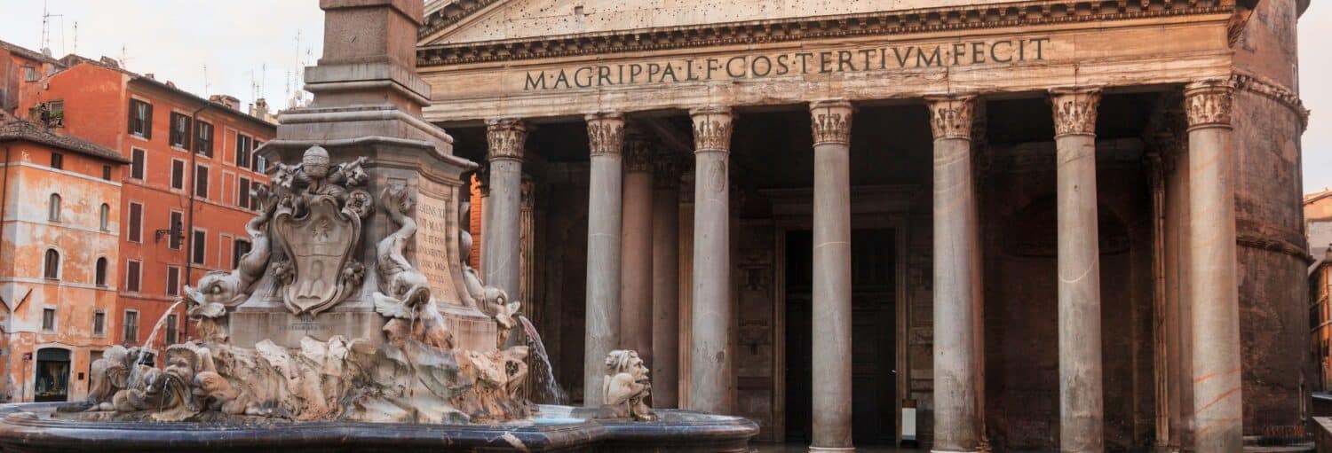 Fonte de pedra com figuras esculpidas em frente às grandes colunas e inscrição do Panteão, em Roma, Itália durante o Ingresso do Panteão de Agripa sem filas + Ônibus turístico de Roma.