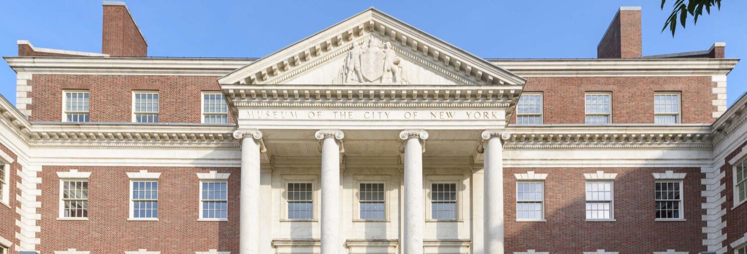 A fachada do Museu da Cidade de Nova York apresenta colunas, paredes de tijolos e um frontão branco com entalhes. A foto é capa do post Ingresso do Museu da Cidade de Nova York.