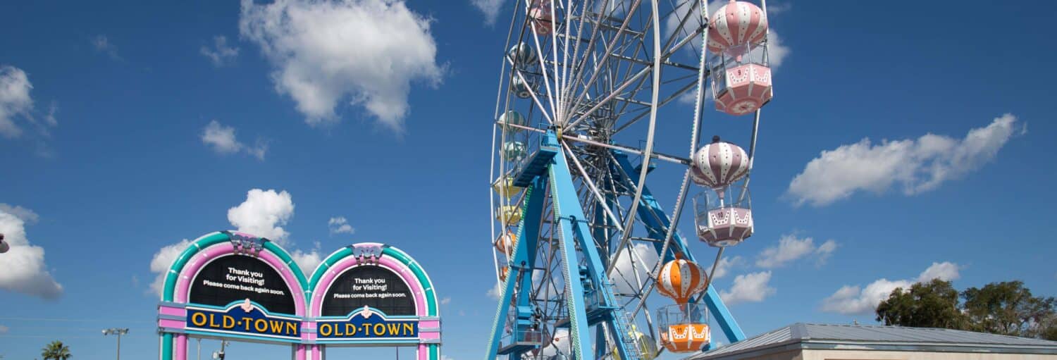 Uma roda gigante e placas coloridas da Cidade Velha sob um céu azul com nuvens esparsas durante o dia durante o Ingresso de 1 ou 2 atrações de Old Town Entertainment District