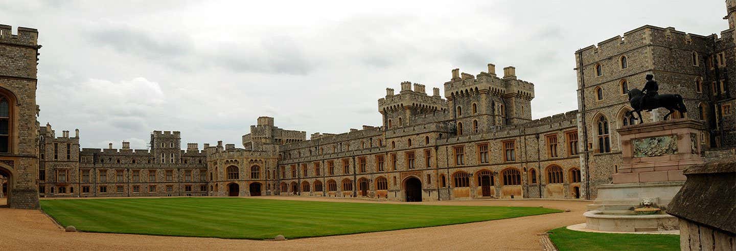 Uma foto do Castelo de Windsor com um jardim na frente e um céu nublado.