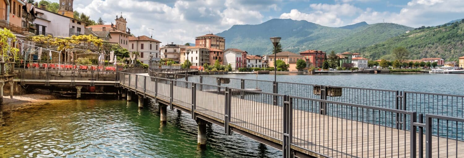 Uma ponte sobre um lago que leva até uma cidade costeira italiana. Excursão ao Lago de Como e Lugano