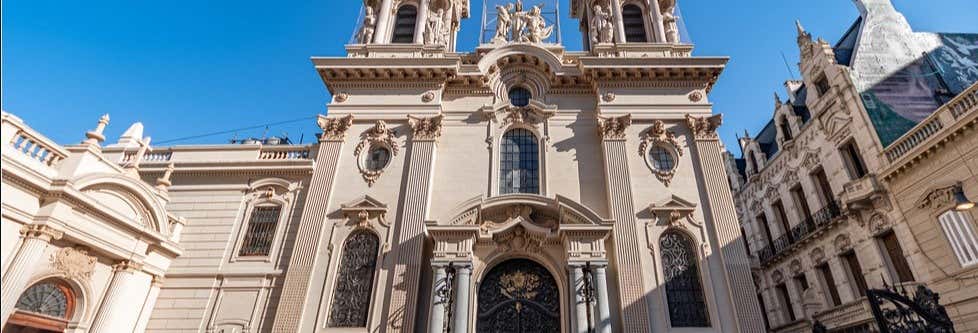 Fachada ornamentada de uma igreja histórica com janelas em arco, estátuas e torres gêmeas contra um céu azul claro no Free tour do Papa Francisco.