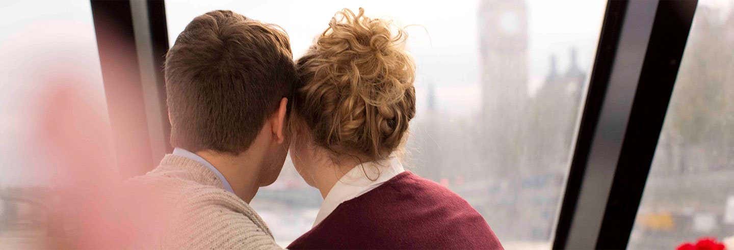 Um homem à esquerda e uma mulher à direita, ambos de costas, encostados um no outro em um passeio de barco com almoço