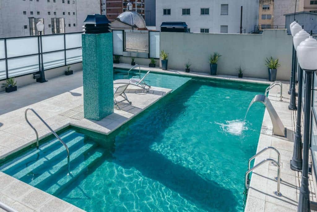 Piscina retangular na cobertura com água limpa, duas espreguiçadeiras, vasos de plantas e prédios ao fundo, na propriedade do Esplendor by Wyndham Buenos Aires Tango.