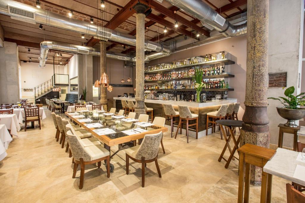 Restaurante moderno e espaçoso, com mesas postas, cadeiras almofadadas, teto alto e um bar totalmente abastecido ao longo da parede dos fundos, na Cassa Lepage Art Hotel Buenos Aires.