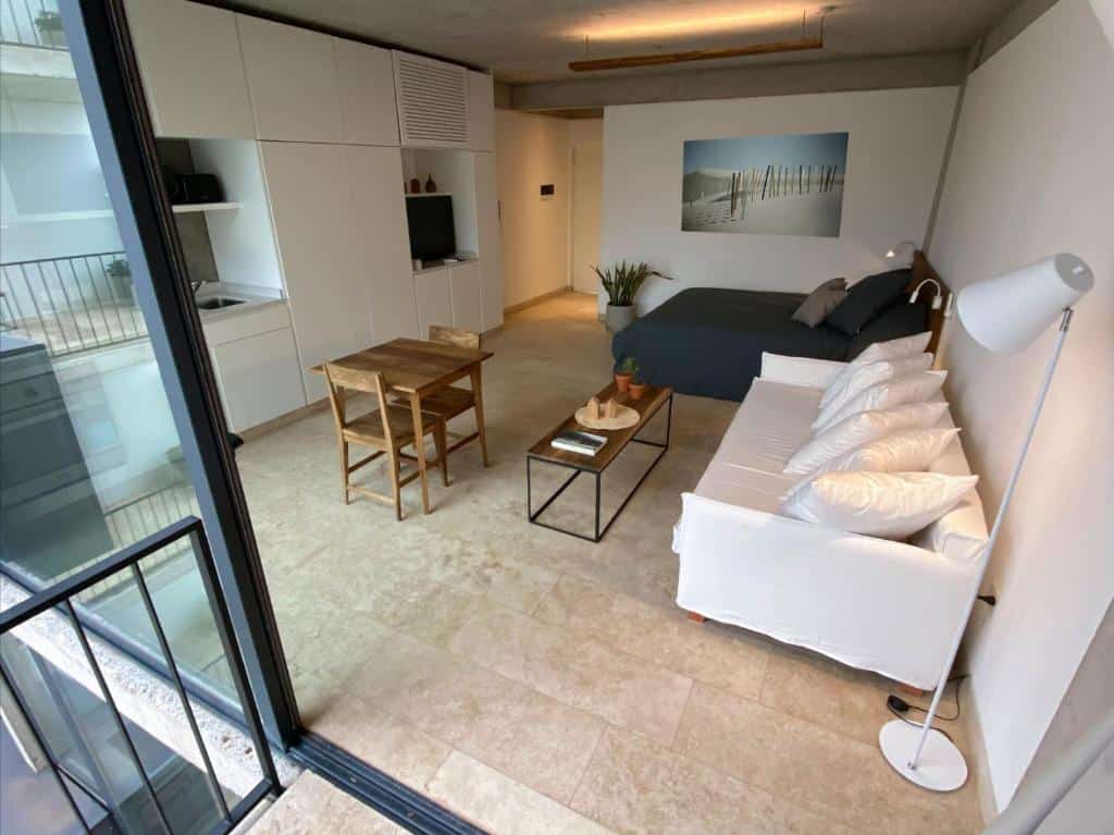 Moderno apartamento estúdio com cama, sofá, mesa de jantar e cozinha compacta, com vista para a varanda de vidro, no Ara Homes Buenos Aires.