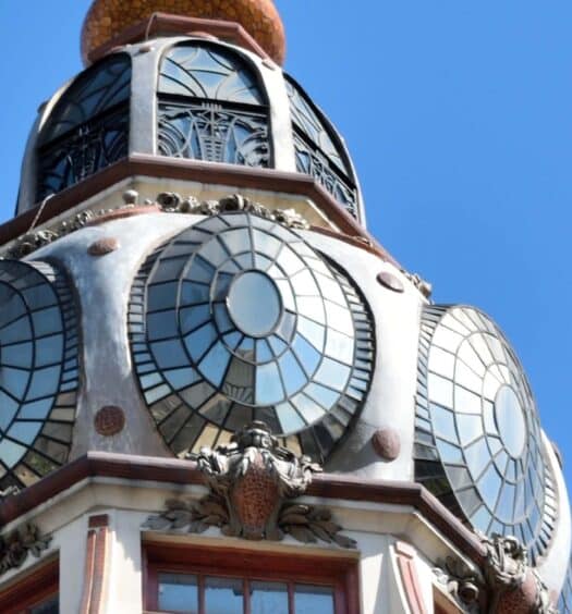 Close-up da cúpula de um edifício com vários mostradores de relógio circulares grandes em um céu azul claro. Imagem para ilustrar post sobre tour das cúpulas de Buenos Aires.