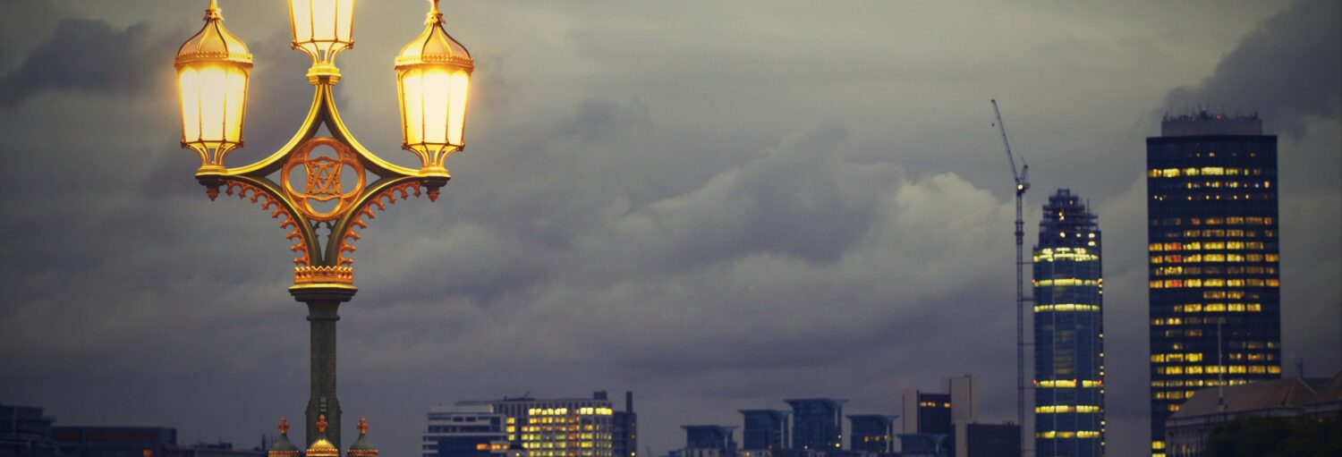Um céu escuro e nublado, um poste iluminado à esquerda e prédios à direita. Free tour dos fantasmas, demônios e assassinatos