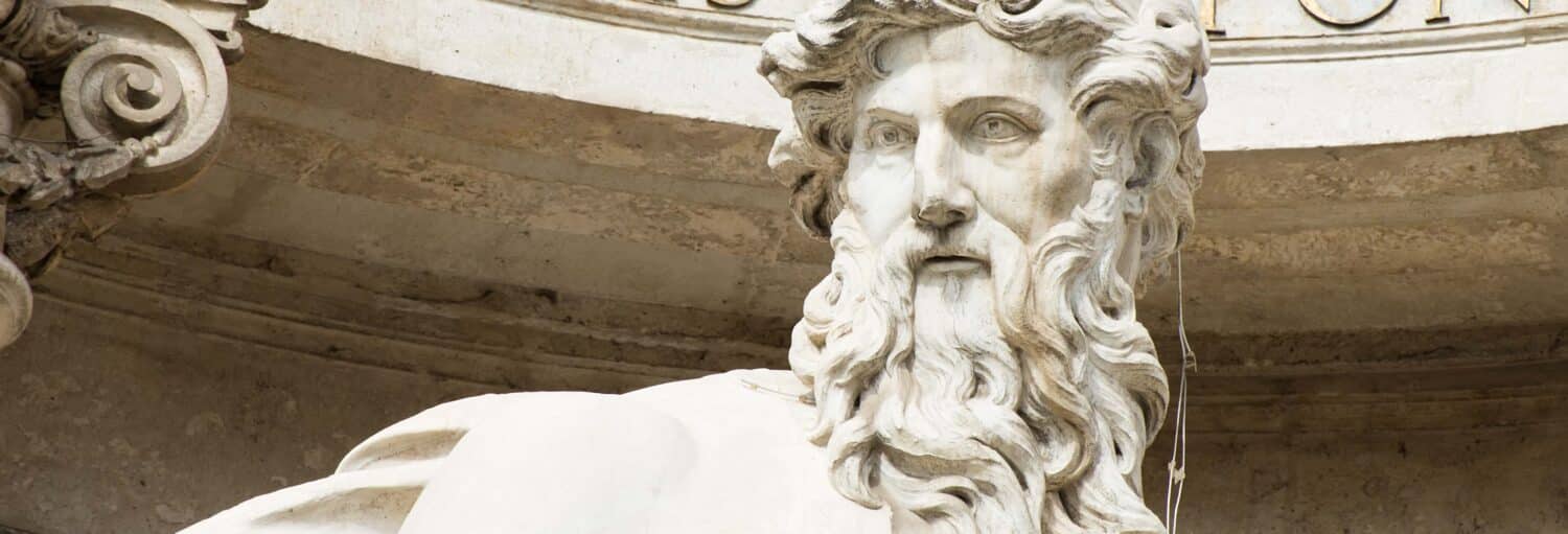 Close-up de uma estátua de mármore barbada com características faciais detalhadas e cabelos ondulados, sobre um fundo de pedra no Tour privado por Roma