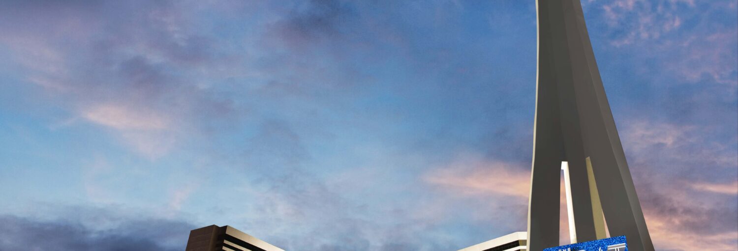 A imagem mostra o The Strat Tower em Las Vegas ao entardecer. A torre alta e esguia se destaca contra o céu azul com nuvens rosadas. Na base, há um prédio moderno com luzes e painéis eletrônicos iluminados. Imagem para ilustrar post sobre o ingresso das atrações do The Strat Las Vegas.