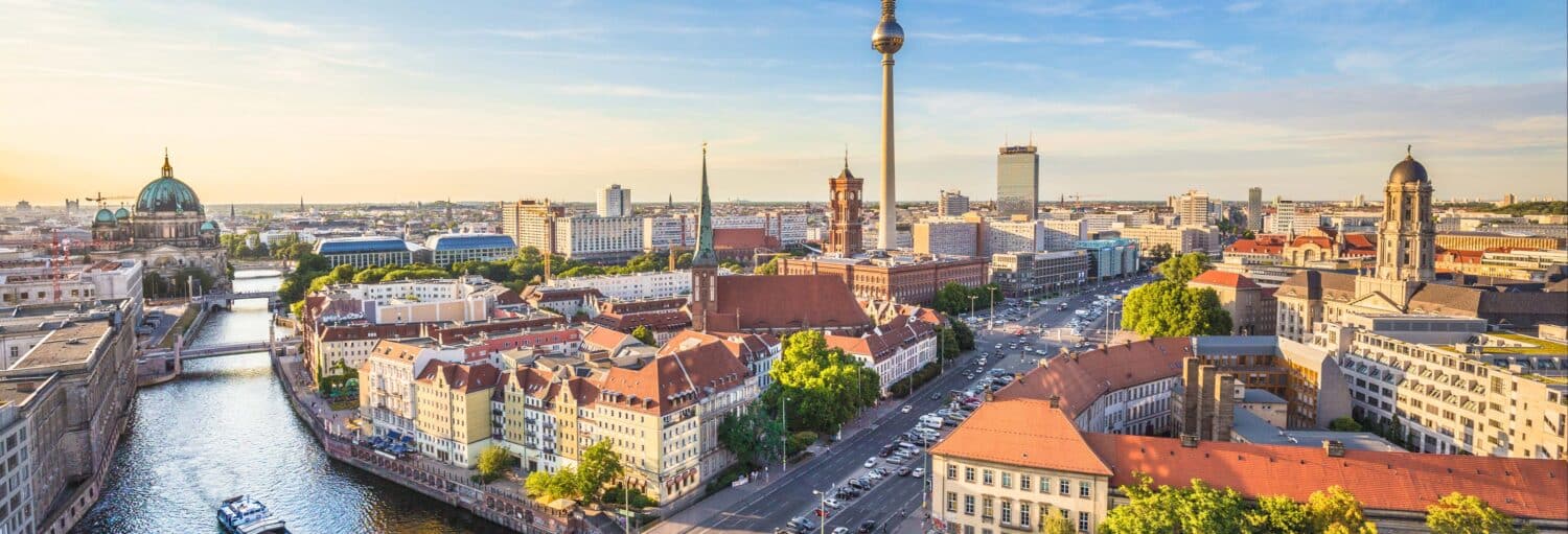 Uma vista panorâmica de Berlim com a torre de TV, o rio, os edifícios históricos e a paisagem urbana em um céu claro. Imagem para ilustrar post sobre o ingresso da Torre TV sem filas.