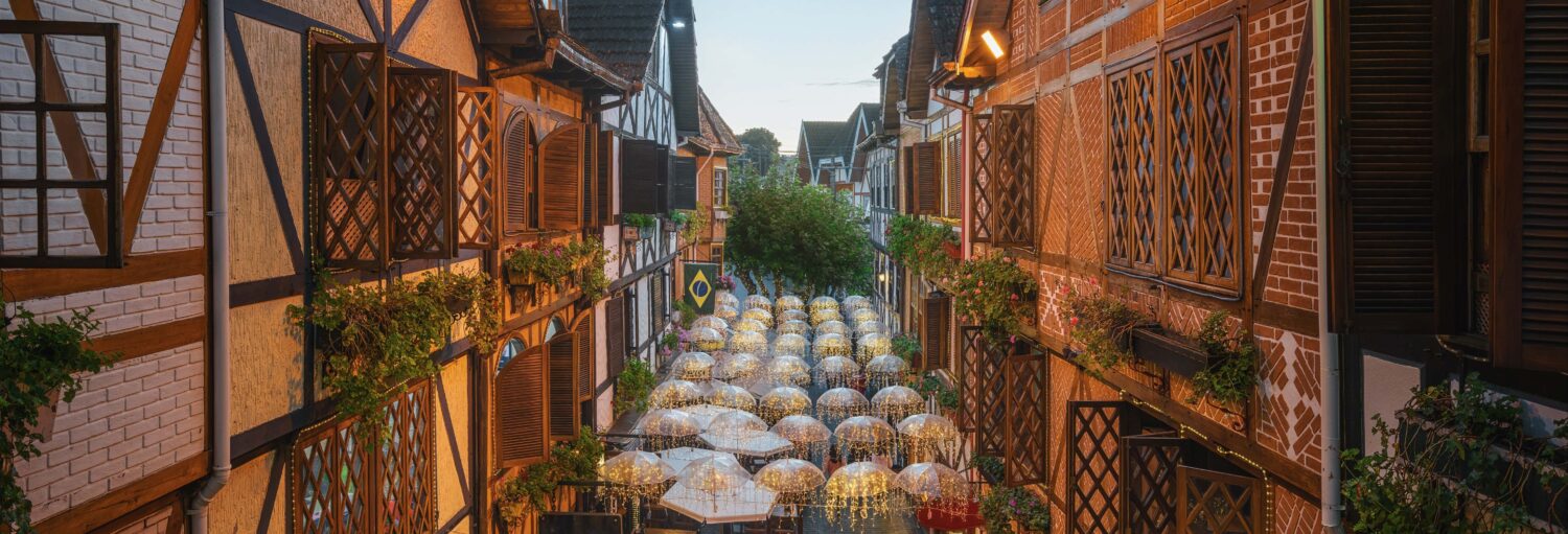 Rua estreita de paralelepípedos com prédios de madeira, como em uma excursão a Campos do Jordão saindo de SP.