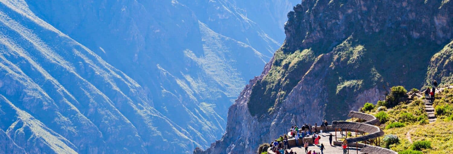 Um grupo de pessoas está em uma plataforma de observação de pedra sinuosa com vista para um cânion de montanha profundo e acidentado à luz do dia na Excursão privada a Killarumiyoq, Tarawasi e mirante de Chonta