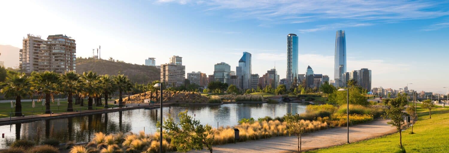 O horizonte de uma cidade com arranha-céus modernos, um parque com um lago e uma trilha de caminhada sob um céu claro. A foto é capa do post do Free tour pelo bairro de Providencia.