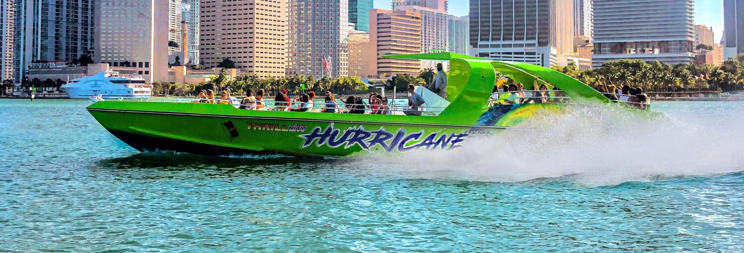 Uma lancha verde brilhante chamada "Hurricane" passa por prédios altos em um passeio de lancha por Miami.