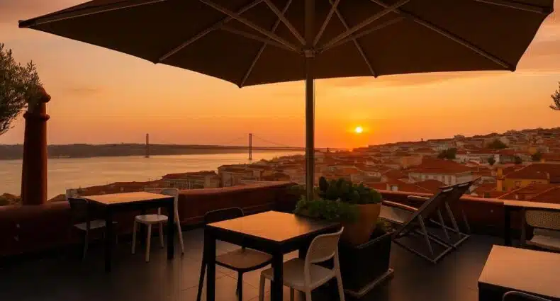 Terraço ao ar livre com mesas, cadeiras e guarda-sol com vista para um rio e uma ponte ao pôr do sol, com vista para os telhados da cidade, no Monte Belvedere Hotel by Shiadu, para representar onde ficar em Lisboa.