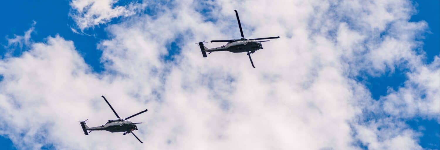 Dois helicópteros sobrevoam o céu, ilustrando um passeio privado de helicóptero por São Paulo.