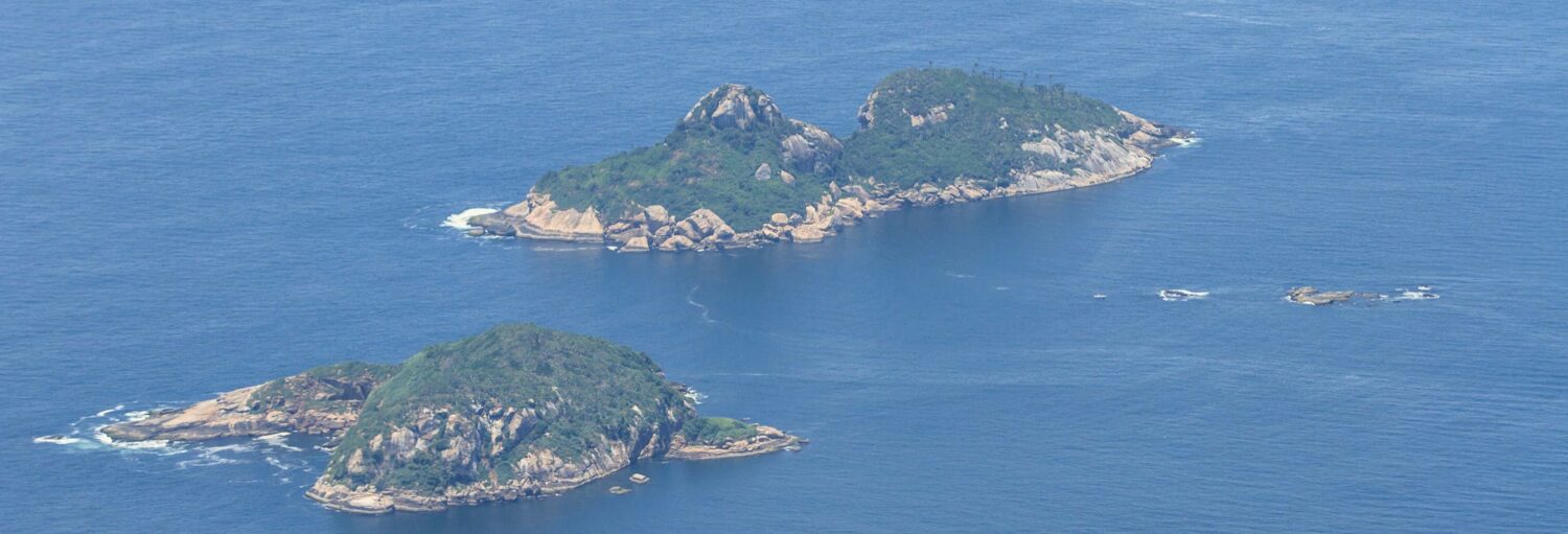 Vista aérea de duas ilhas verdes e rochosas - ideal para um passeio de lancha pelas ilhas da Gigóia e Tijuca.