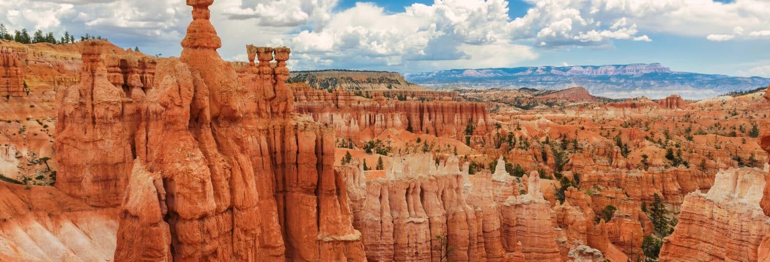Penhascos e hoodoos de rocha vermelha sob um céu parcialmente nublado em uma vista panorâmica do Bryce Canyon National Park, Utah. Imagem para ilustrar post sobre tour de 3 dias pelo Grand Canyon e Utah.