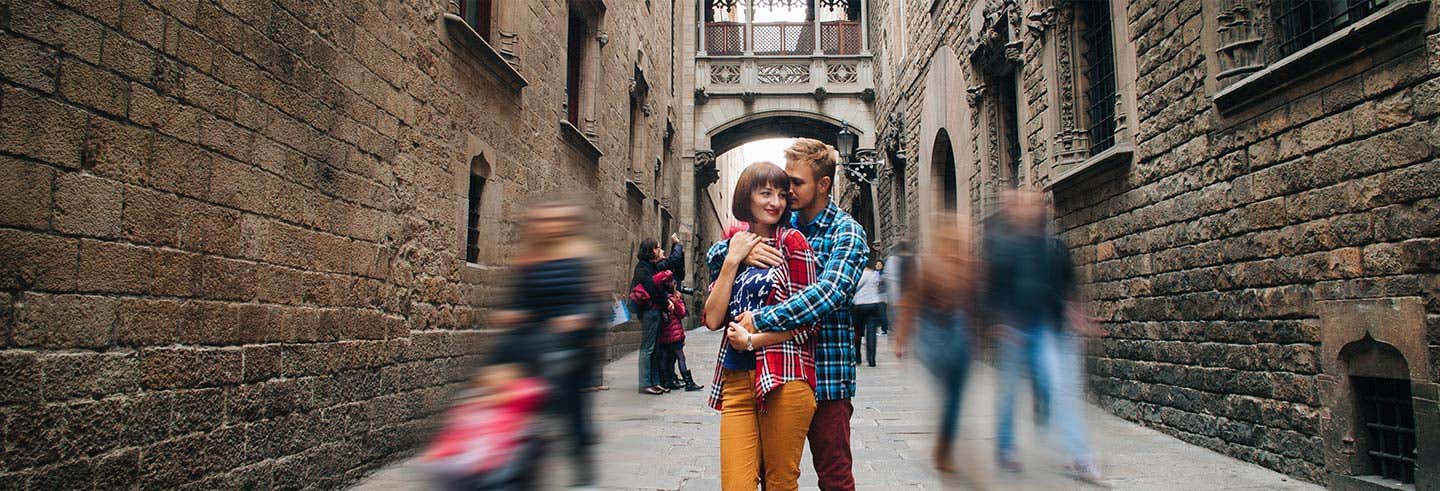 Um casal está junto em um beco estreito de pedra enquanto as pessoas passam, criando um efeito de movimento borrado ao redor deles. A imagem ilustra o post sobre Andaluzia, Valência e Barcelona em 7 dias.