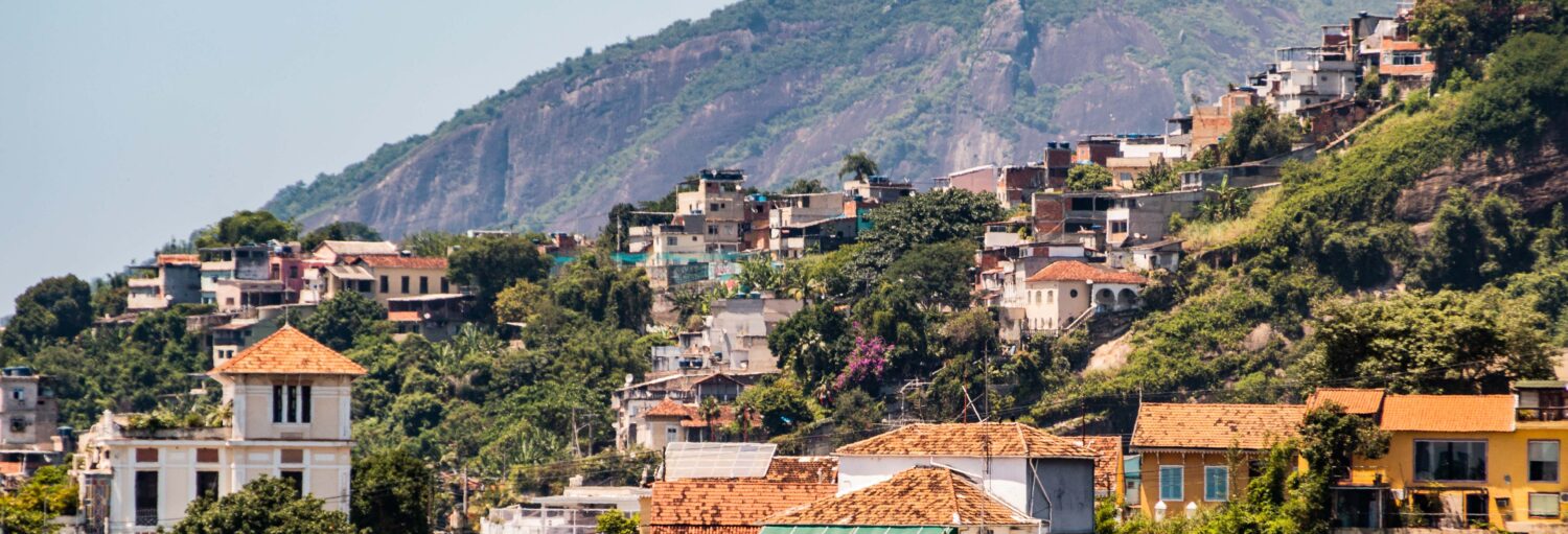 Bairro de encosta com casas e vegetação, perfeito para um tour por Santa Teresa e Rio antigo sob um céu claro.
