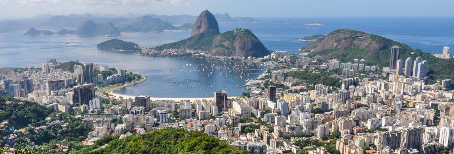Vista aérea do Rio de Janeiro com o Pão de Açúcar, a Baía de Guanabara e os prédios da cidade sob um céu claro. A imagem ilustra o post sobre Tour da cultura judaica pelo Rio de Janeiro.